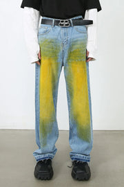 Oversized medium wash denim jeans with yellow and green spray paint effect.