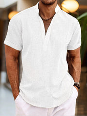Men's white short sleeve cotton blend henley shirt with buttoned placket and mandarin collar.