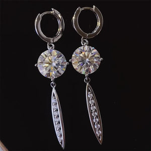 Silver moissanite orb dangle earrings with pavé accents on black background