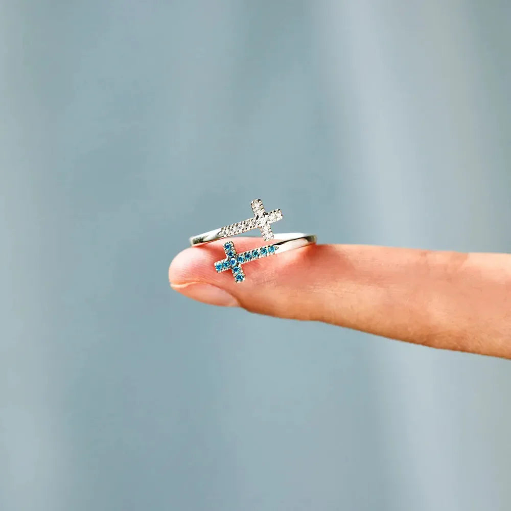 Sterling silver ring with intertwined crosses, one with clear stones, one with blue zircon.