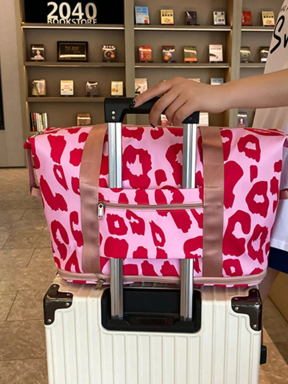 Vibrant leopard print travel bag with pink and red pattern, two handles, and front zipper pocket.