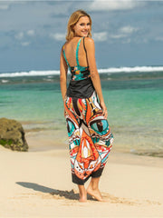 Pareo wrap with multicolor owl graphic print and black trim, worn by a model on a beach.