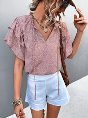 Pink ditsy print blouse with ruffle sleeves and tie neck, styled with white shorts.