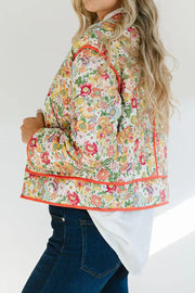 Floral quilted jacket with contrast piping in orange-red, featuring a vibrant floral print and casual cut.