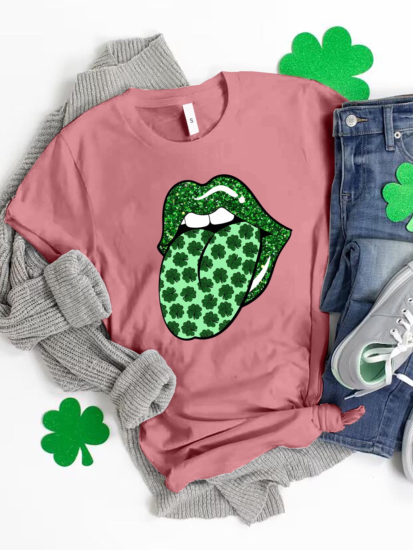 Pink t-shirt with a glittery green tongue graphic featuring a shamrock pattern.
