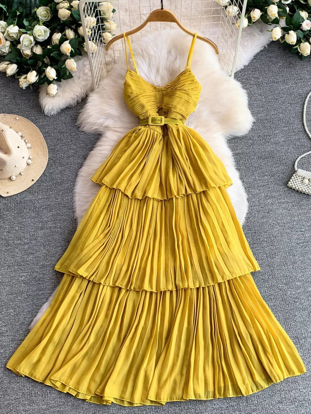 Yellow belted pleated midi dress with spaghetti straps and tiered skirt.