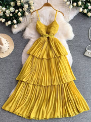 Yellow belted pleated midi dress with spaghetti straps and tiered skirt.