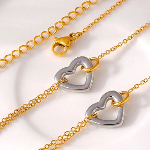 Two-tone heart charm bracelet with gold chain and clasp.