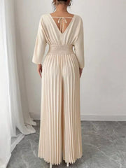 Beige pleated wide-leg jumpsuit with cinched waist and V-neck tie back.
