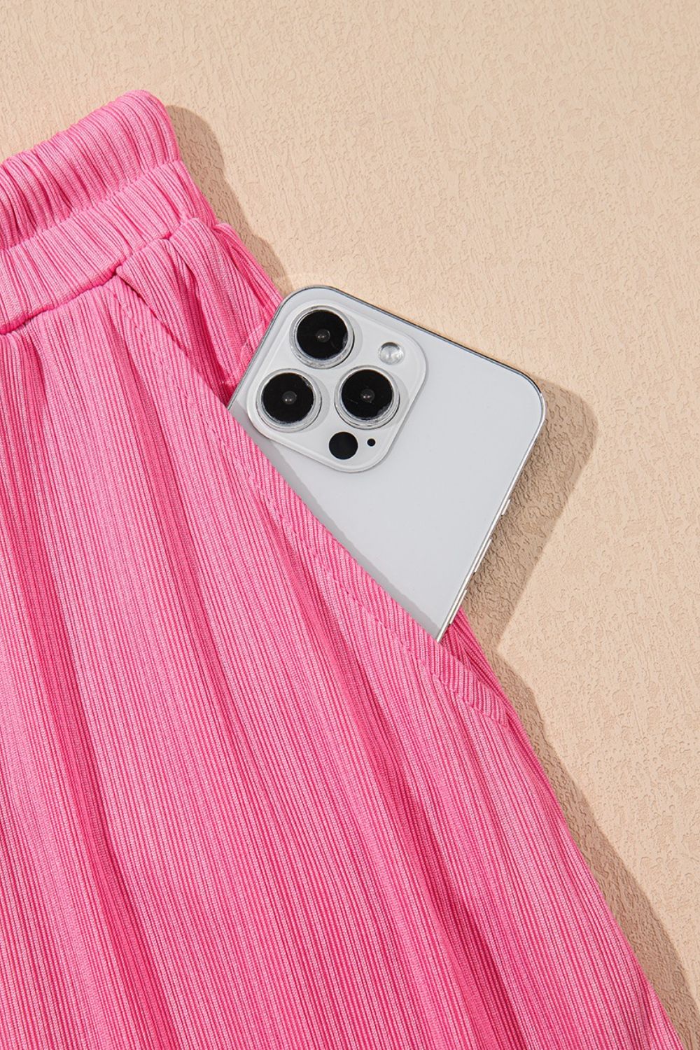 Pink ribbed skirt set with drawstring waist and pocket detail, showing a phone.