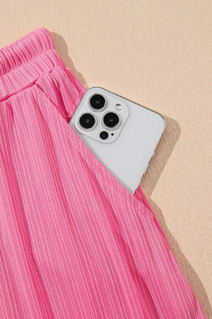 Pink ribbed skirt set with drawstring waist and pocket detail, showing a phone.