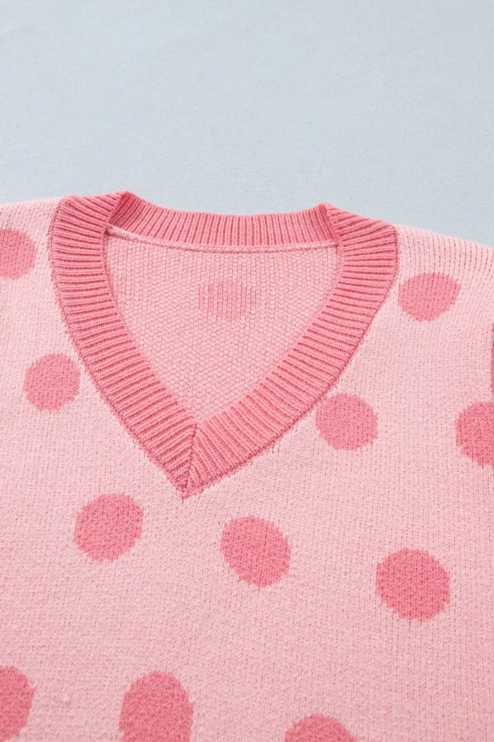 Pink polka dot knit cardigan with V-neck and ribbed trim.
