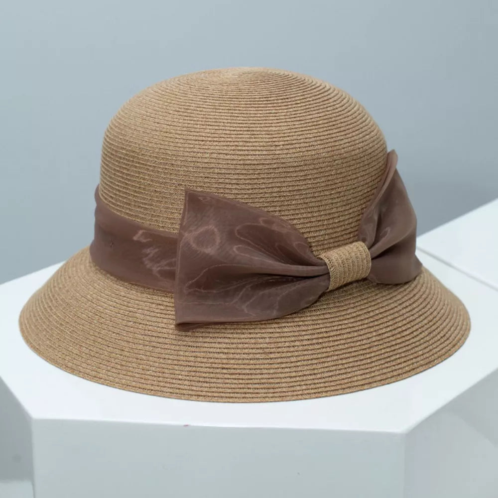 Chic cloche sun hat in beige straw with a sheer ribbon bow detail.