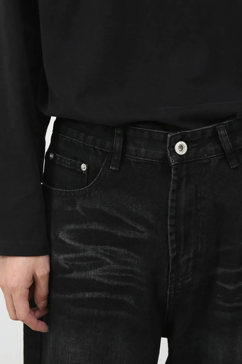 Faded black denim baggy trousers with a button fly and silver hardware.