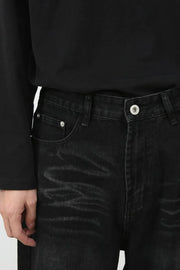 Faded black denim baggy trousers with a button fly and silver hardware.