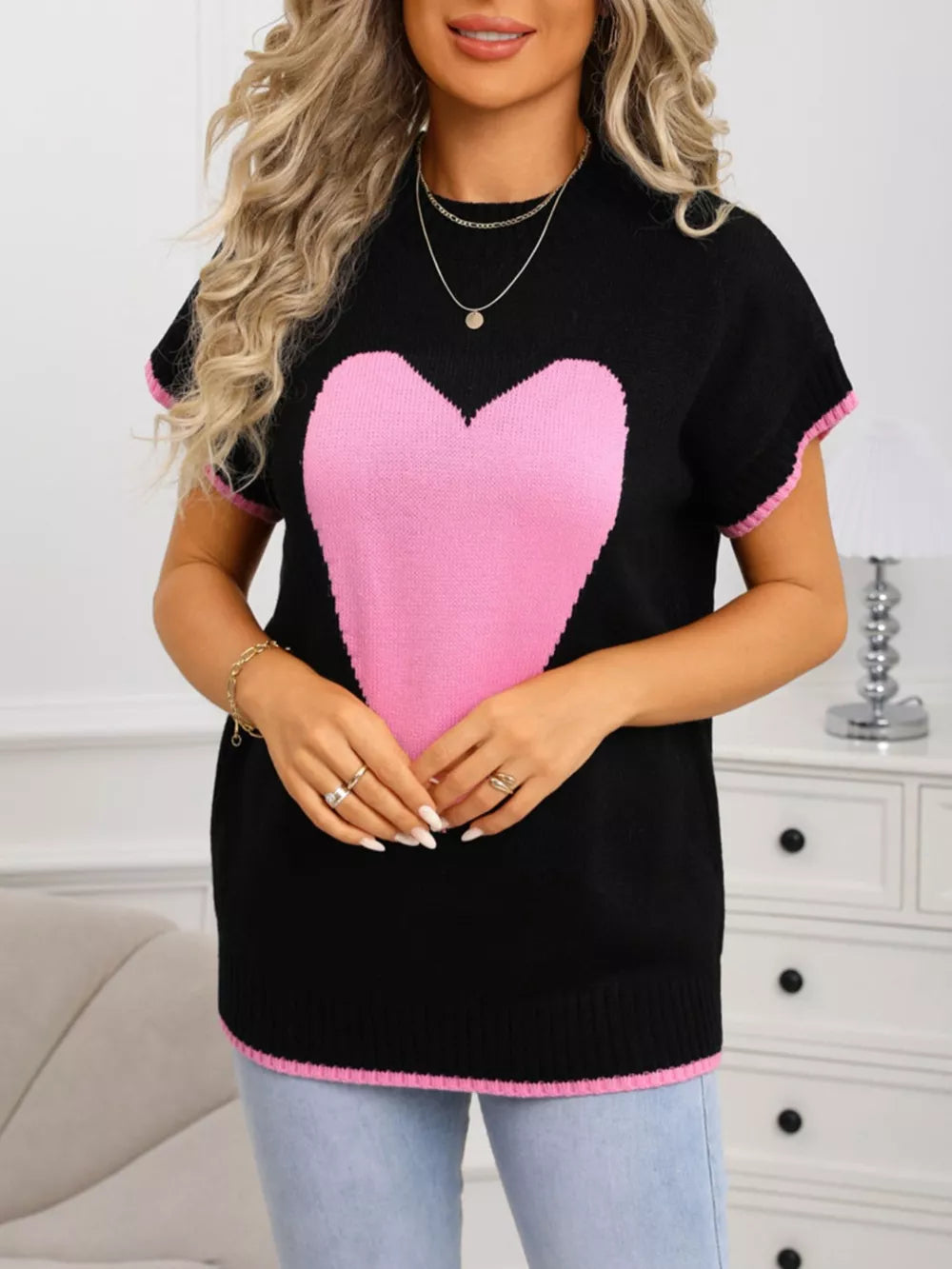 Black acrylic knit top with pink heart graphic, crew neck, short sleeves, and ribbed accents.