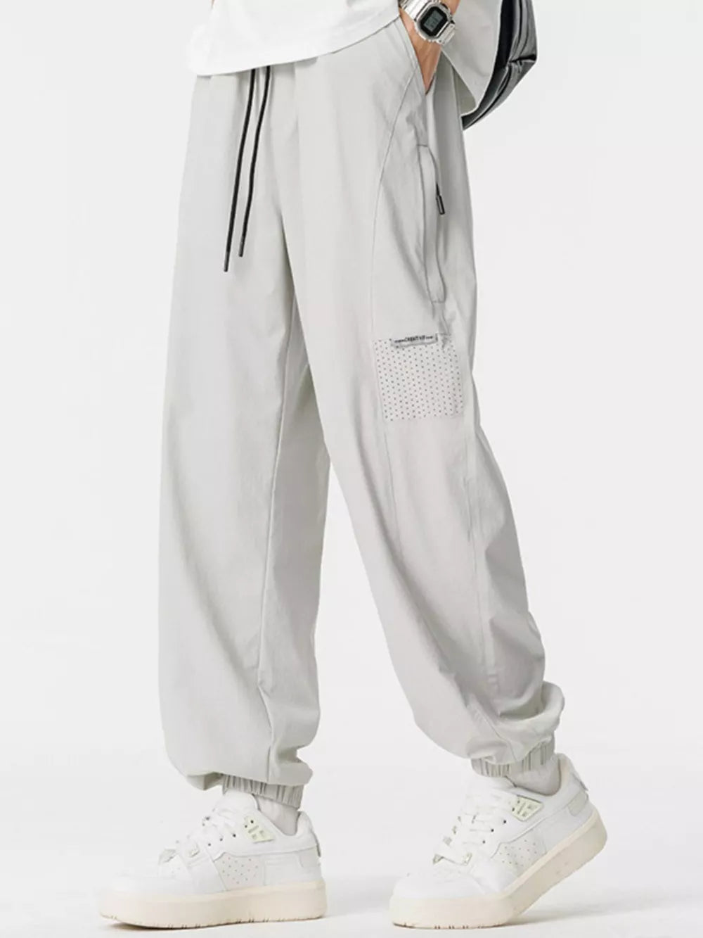 Lightweight grey jogger sweatpants with drawstring and zippered pocket detail.