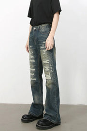 Distressed flare jeans in medium wash denim with graffiti-style rips and a comfortable cotton blend.