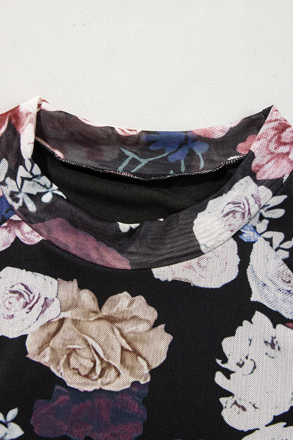 Black mesh blouse with romantic floral print and mock neck detail.
