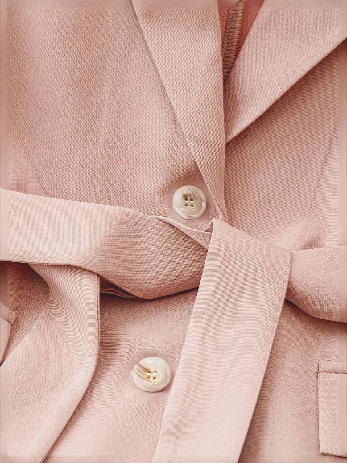 Sleeveless blush blazer with a belted waist and button detail