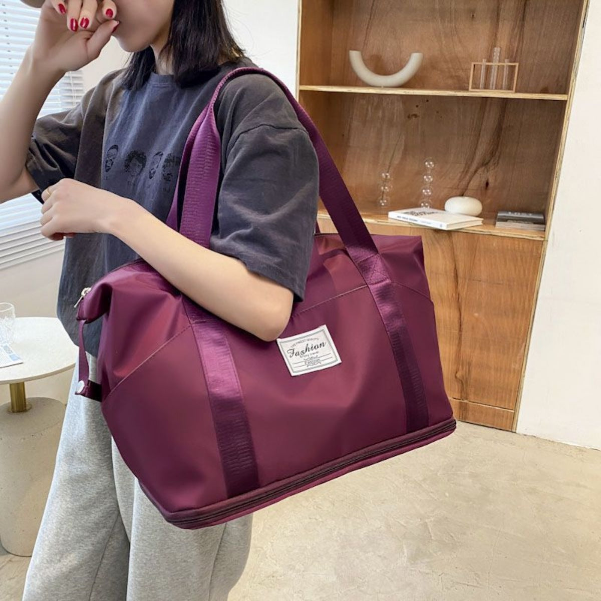 Deep purple travel duffel bag with white "Fashion" label and satin straps.