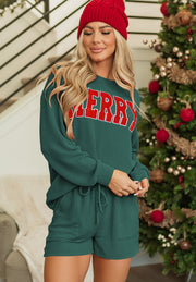 Textured green loungewear set with red "Merry" graphic on crewneck sweatshirt and drawstring shorts.