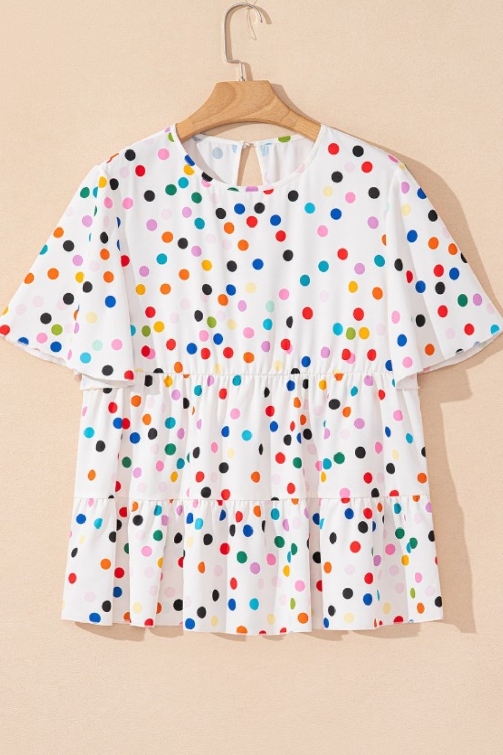 White tiered blouse with rainbow polka dots and flutter sleeves.