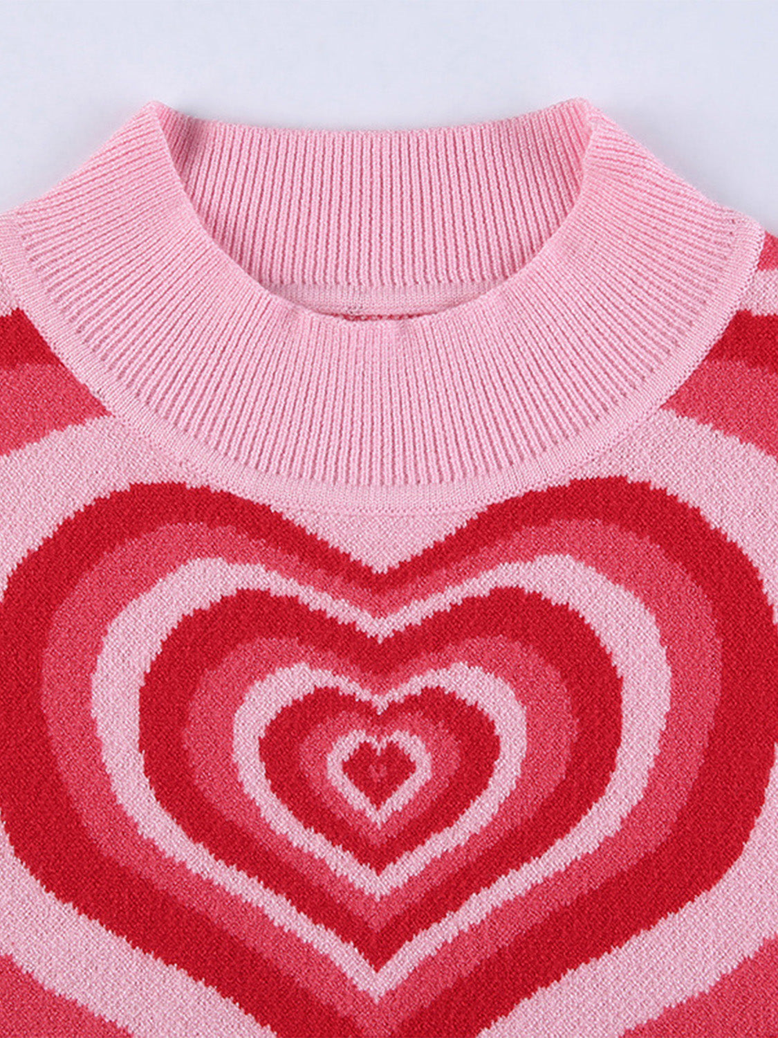 Pink knit tank top with concentric heart intarsia pattern in shades of red and pink.