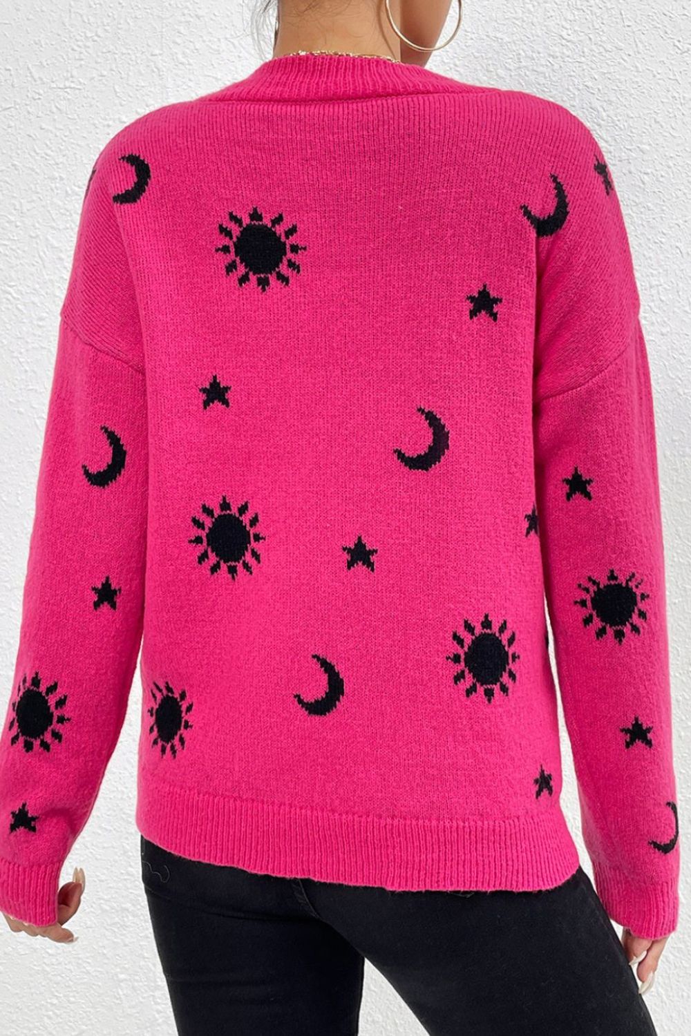 Hot pink acrylic knit sweater with black sun, moon, and star motifs. Mock neck, long sleeves.