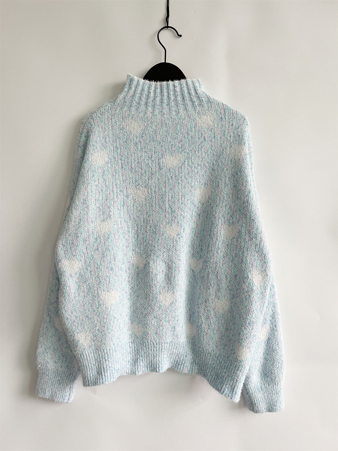 Mint blue acrylic turtleneck sweater with allover white heart motif and textured knit.