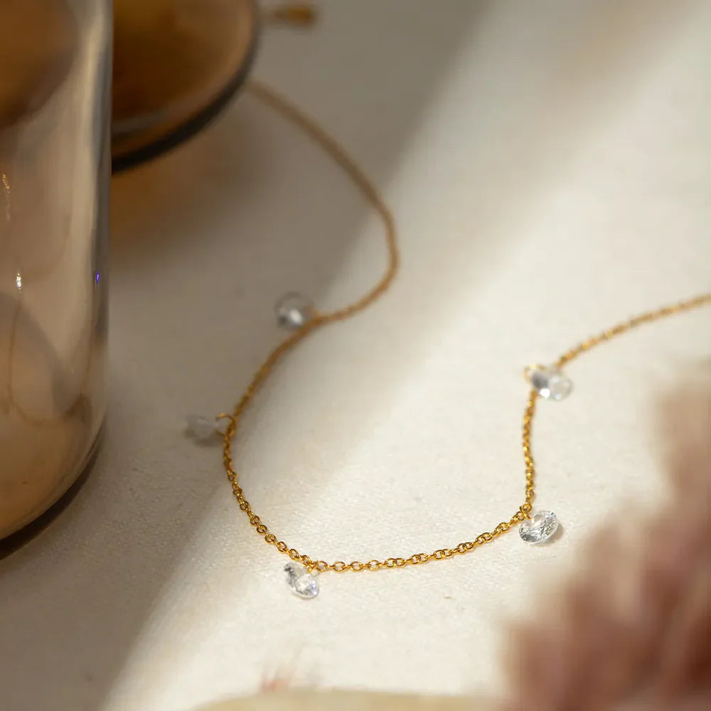 Gold dangling crystal station necklace with delicate chain and scattered clear stones.