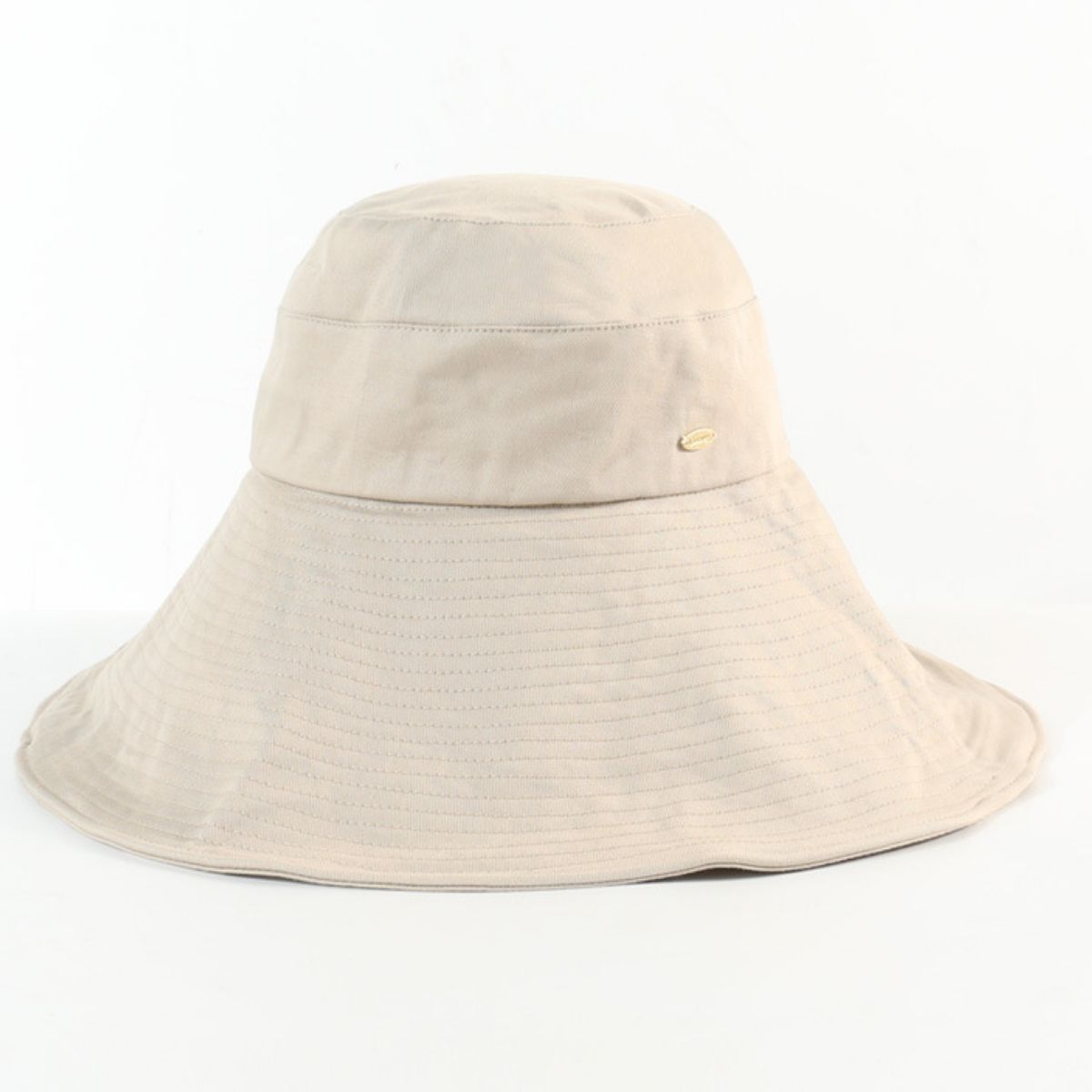 Beige cotton sun hat with wide brim and subtle stitched detail, featuring a small gold emblem.