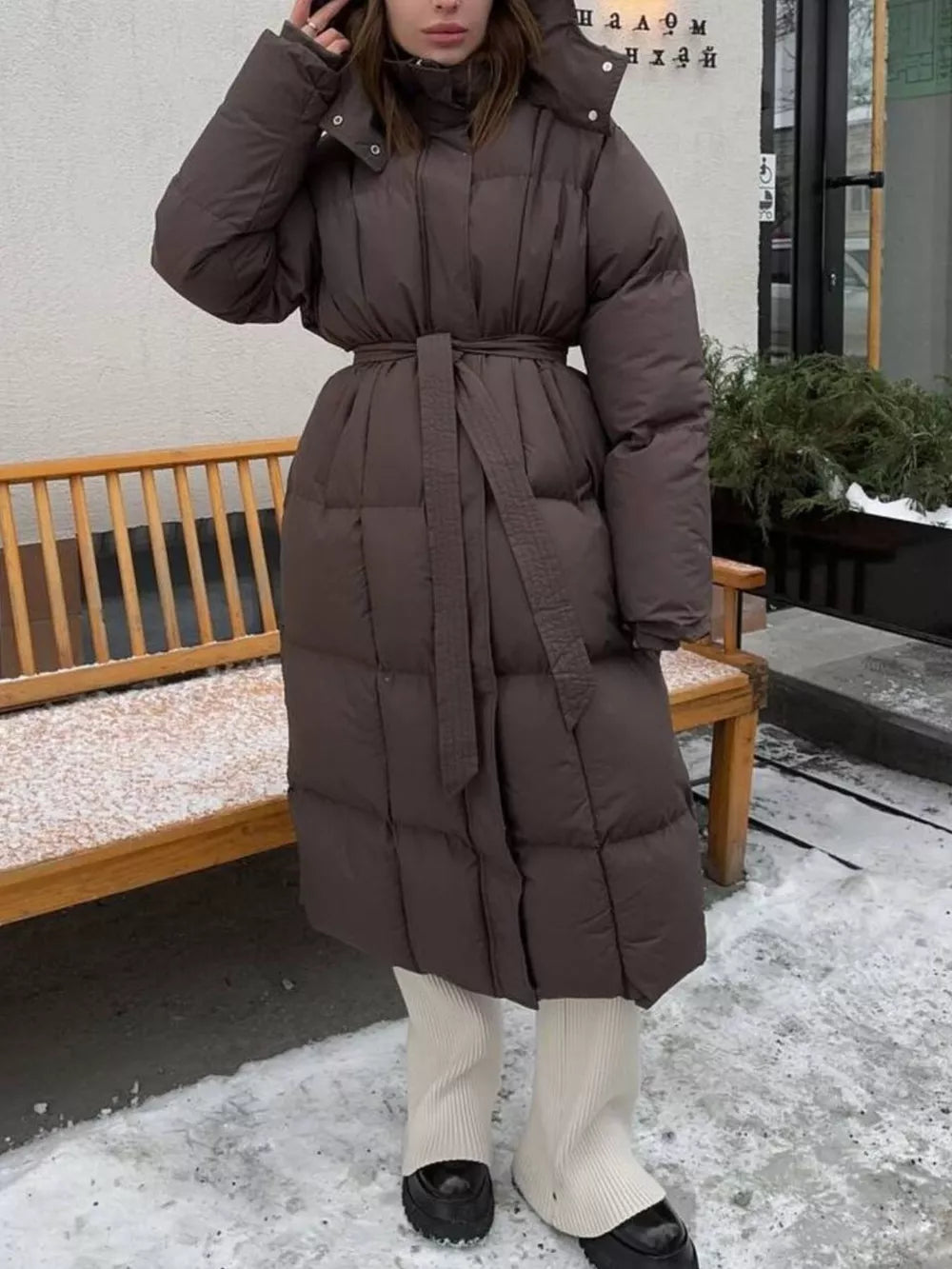 Chic dark brown padded trench coat with tie-belt and hood, full length.