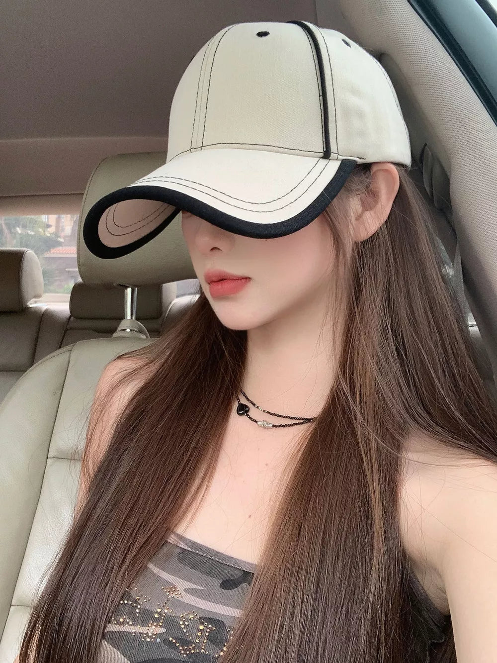 Cream white cotton baseball cap with contrast black stitching and brim detail.