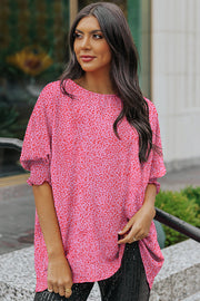 Pink leopard print blouse with smocked short sleeves and a round neckline.