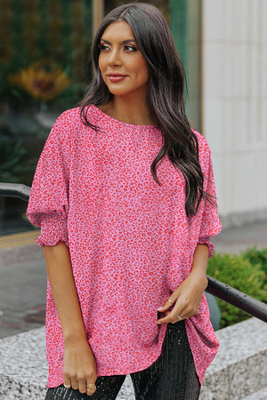 Pink leopard print blouse with smocked short sleeves and a round neckline.
