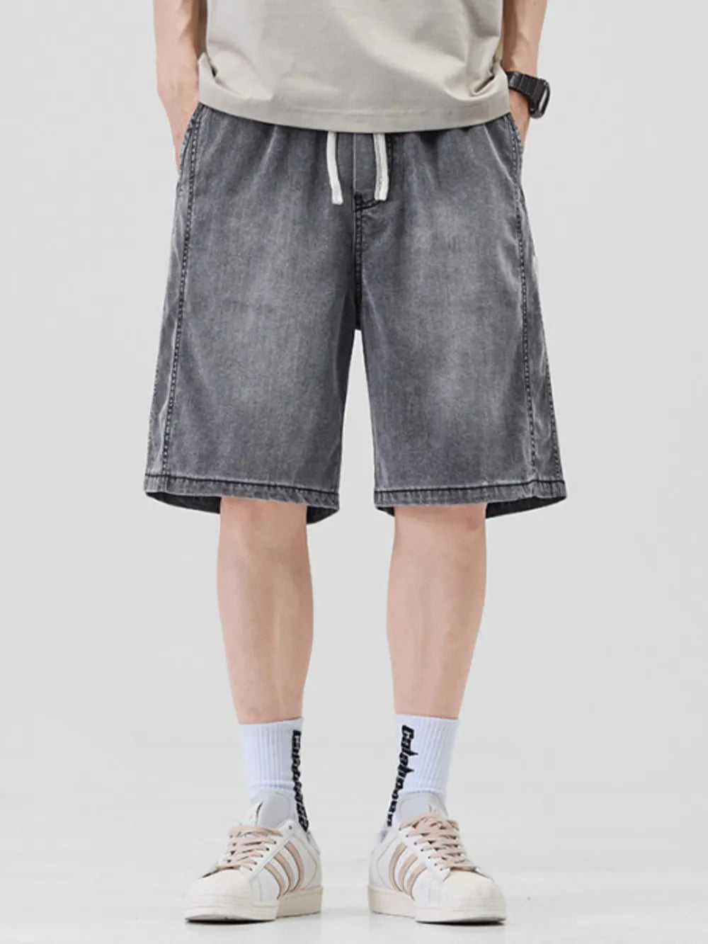 Dark gray denim shorts for him with drawstring waist and loose fit.