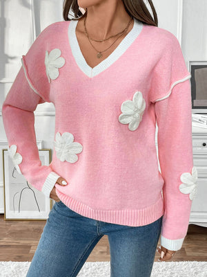 Pink V-neck knit sweater with white floral appliqués and contrast trim.