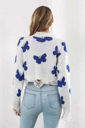 White acrylic cropped sweater with blue butterfly intarsia and frayed hem.