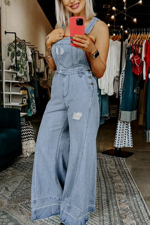 Distressed light wash denim overalls with wide legs and button details.