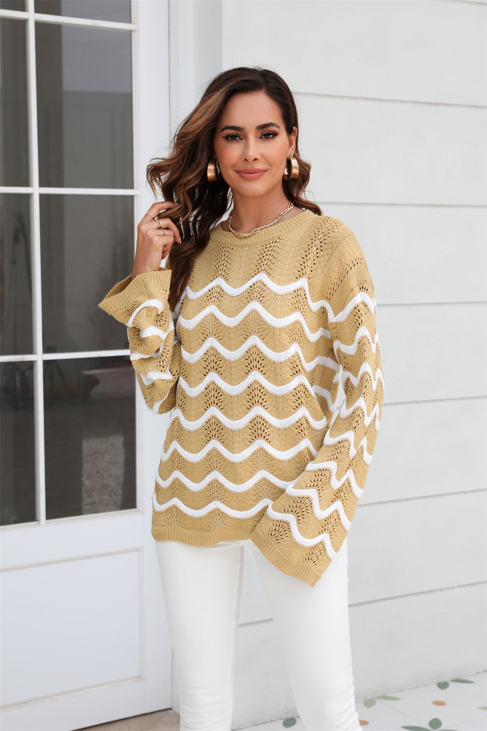 Khaki openwork knit sweater with white wavy stripes and bell sleeves.