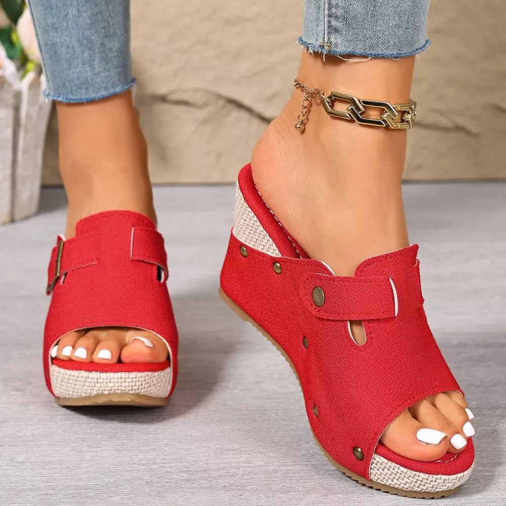 Red wedge sandals with decorative accents and buckle detail, featuring a jute-wrapped sole.