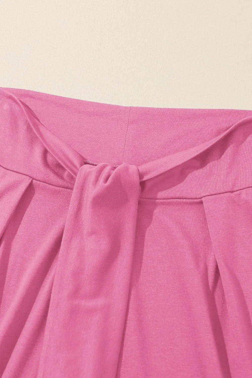 Pink wrap-front palazzo pants with a tie waist detail.