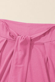 Pink wrap-front palazzo pants with a tie waist detail.