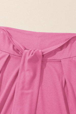 Pink wrap-front palazzo pants with a tie waist detail.