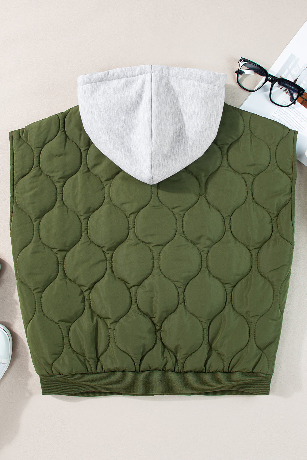 Quilted moss green hooded sleeveless jacket with grey hood and ribbed hem.