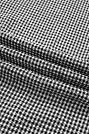 Black and white gingham polyester shirt with ruffled sleeves and bow tie detail.