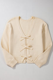 Ivory bouclé knit cardigan with v-neck and three front bow details.