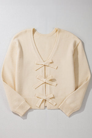 Ivory bouclé knit cardigan with v-neck and three front bow details.