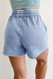 Light blue acid-washed cotton drawstring shorts with pockets and ruffled elastic waistband.
